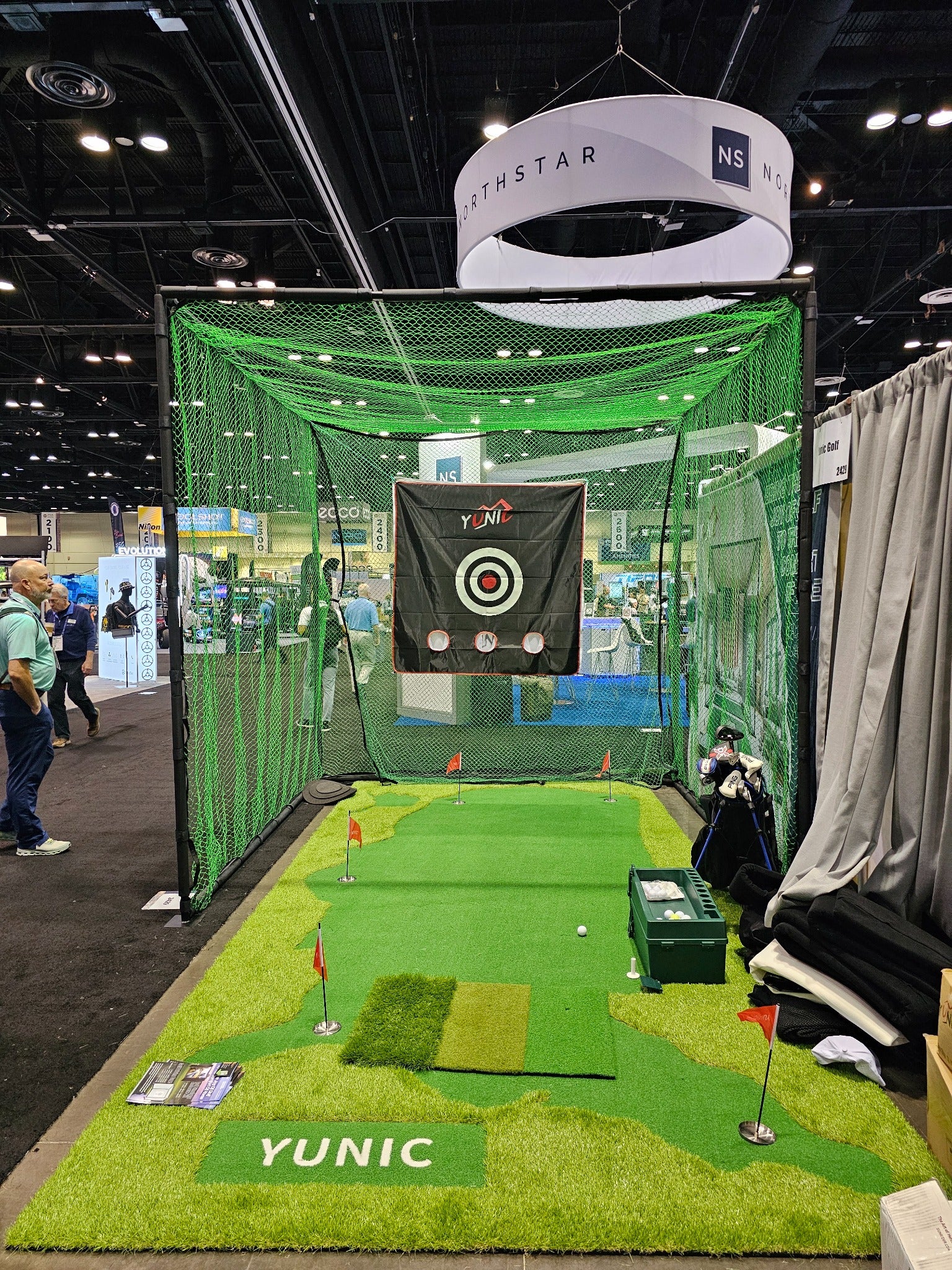 Front view of the YUNIC green-net driving cage and putting greens at the PGA Show.